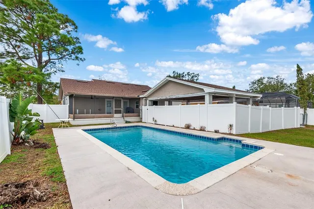 a front view of house with yard swimming pool and trees in the background