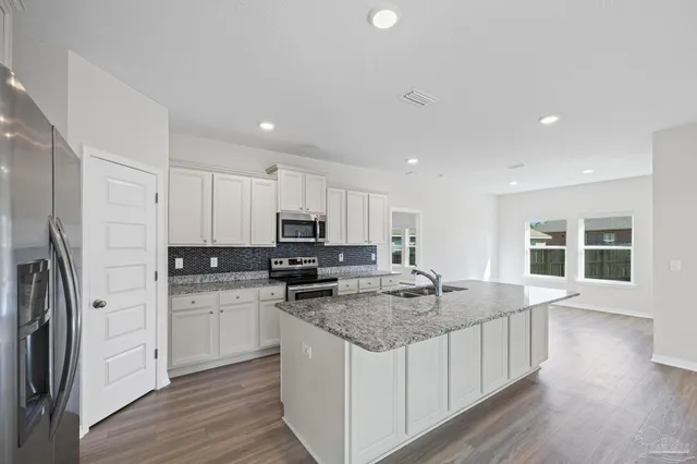 a kitchen with granite countertop a sink a counter space appliances and cabinets