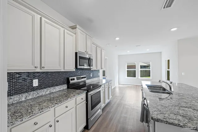 a kitchen with stainless steel appliances granite countertop a sink stove and wooden floor
