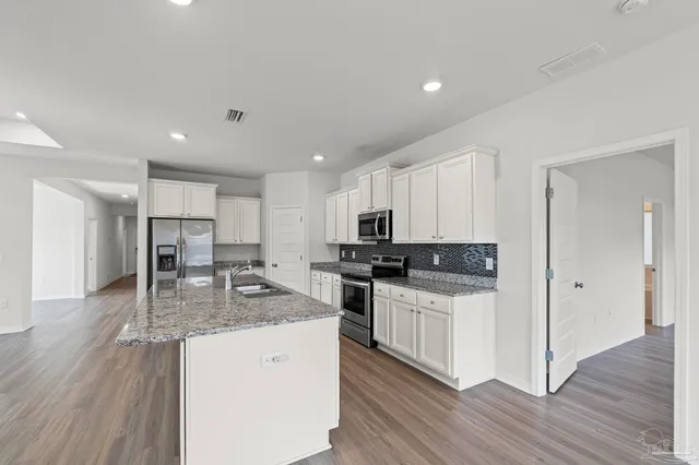 a kitchen with stainless steel appliances granite countertop a stove a sink and a refrigerator