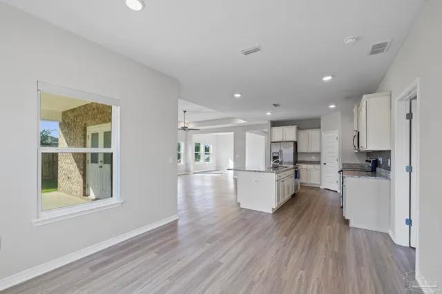 an empty room with wooden floor a ceiling fan and windows