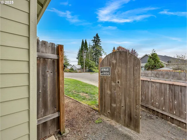 a view of a backyard with large trees and wooden fence