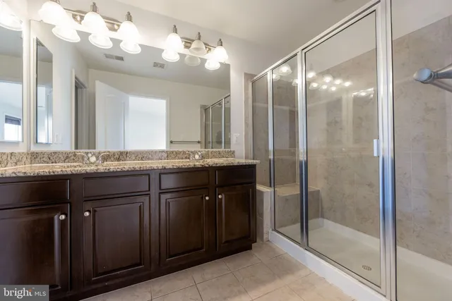 a bathroom with a granite countertop sink a mirror and a shower