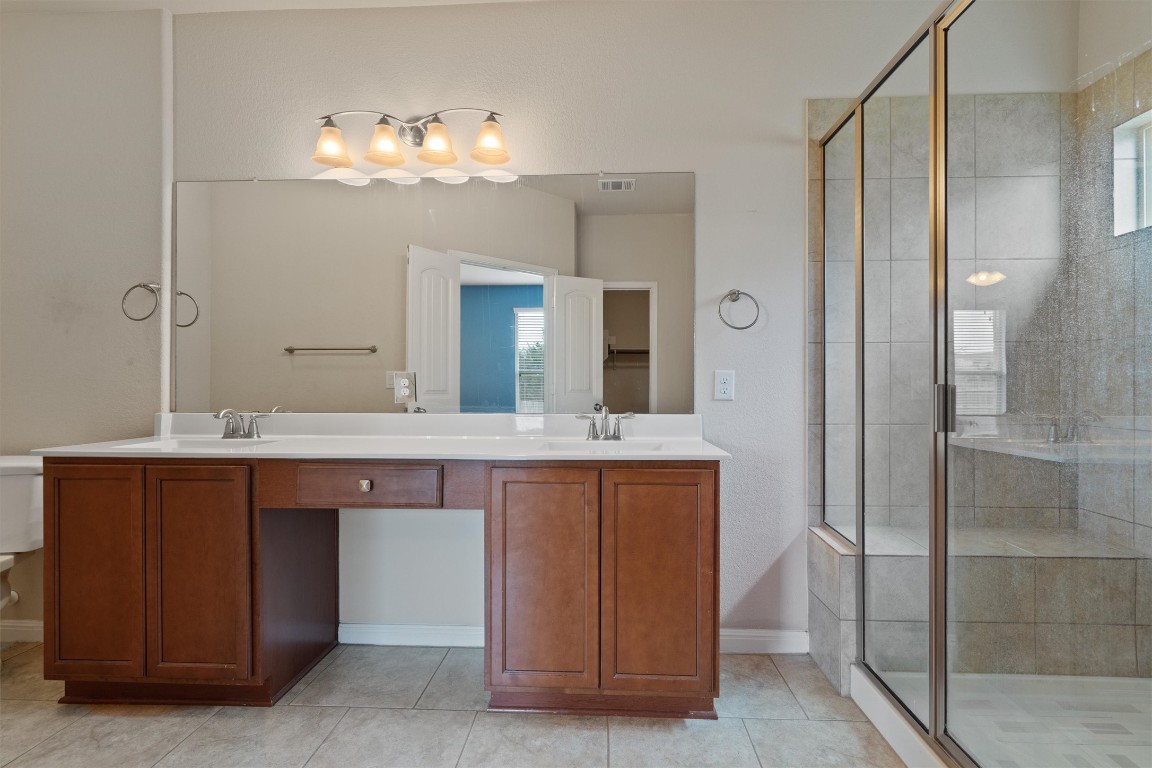 533 Jess Maynard Trail Leander, TX 78641 - Photo 12 of 24 Full bath with a stall shower, double vanity, and light tile patterned floors