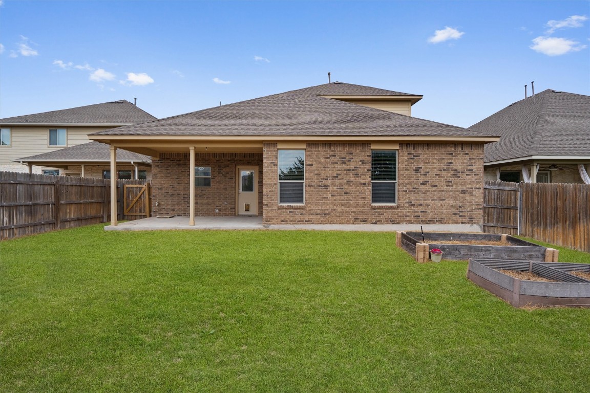 533 Jess Maynard Trail Leander, TX 78641 - Photo 21 of 24 Rear view of house featuring a patio area, a garden, brick siding, roof with shingles, and a fenced backyard