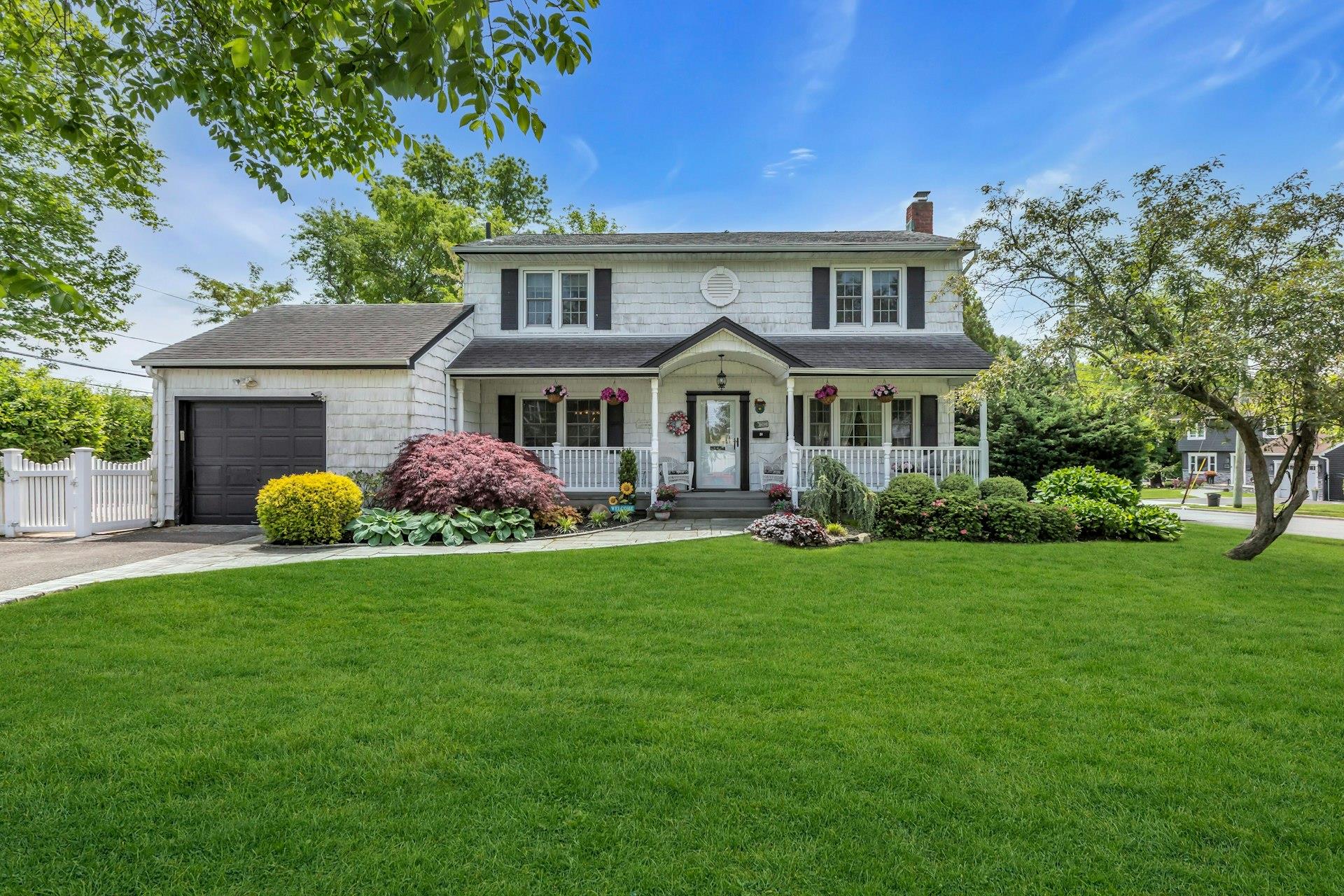 View of front of property with covered porch, a chimney, an attached garage