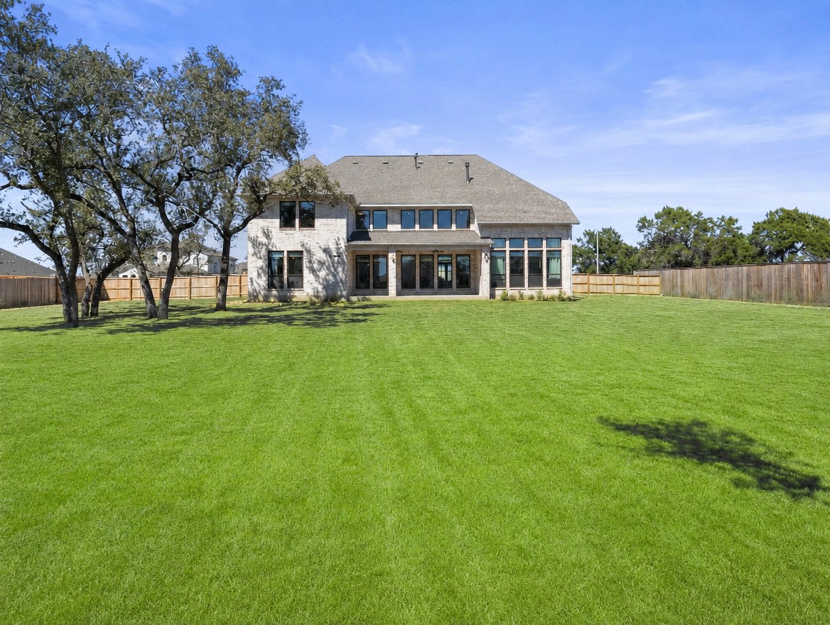1440 Riva Ridge Drive Leander, TX 78641 - Photo 30 of 37 A well-maintained lawn stretches behind a residence with extensive window views.