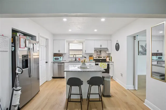 a kitchen with refrigerator and chairs