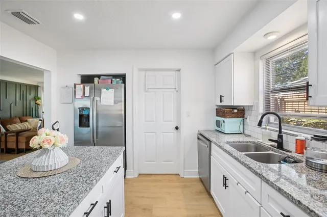 a kitchen with stainless steel appliances granite countertop a sink refrigerator and cabinets