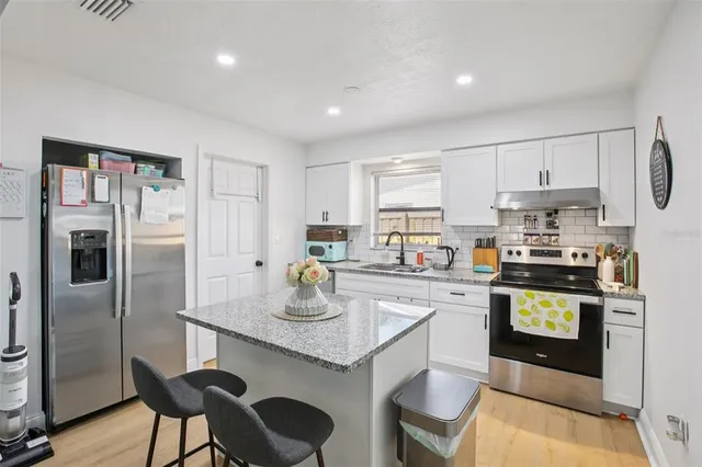 a kitchen with a refrigerator a stove a sink and dishwasher with white cabinets