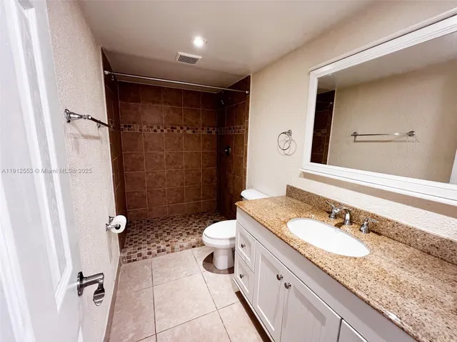 a bathroom with a granite countertop sink toilet and shower