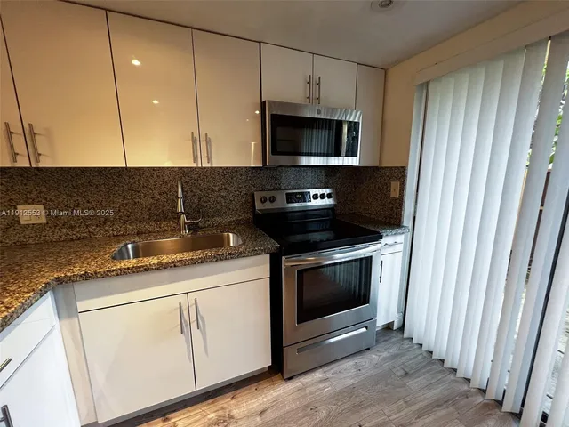 a kitchen with stainless steel appliances granite countertop a stove a microwave and a white cabinets