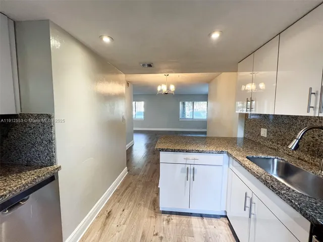 a kitchen with granite countertop a sink stove and cabinets