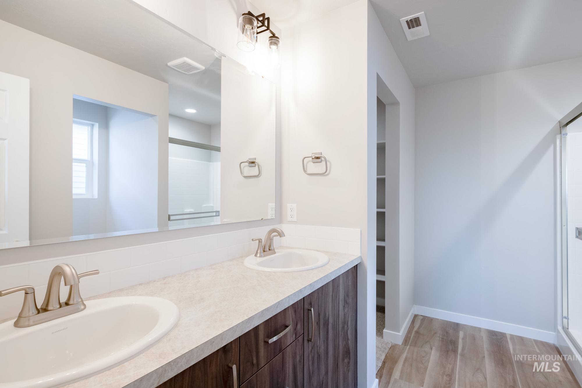7256 South Menzingers Avenue Meridian, ID 83642 - Photo 20 of 23 Full bath with a shower stall, double vanity, light wood-style flooring, and a spacious closet