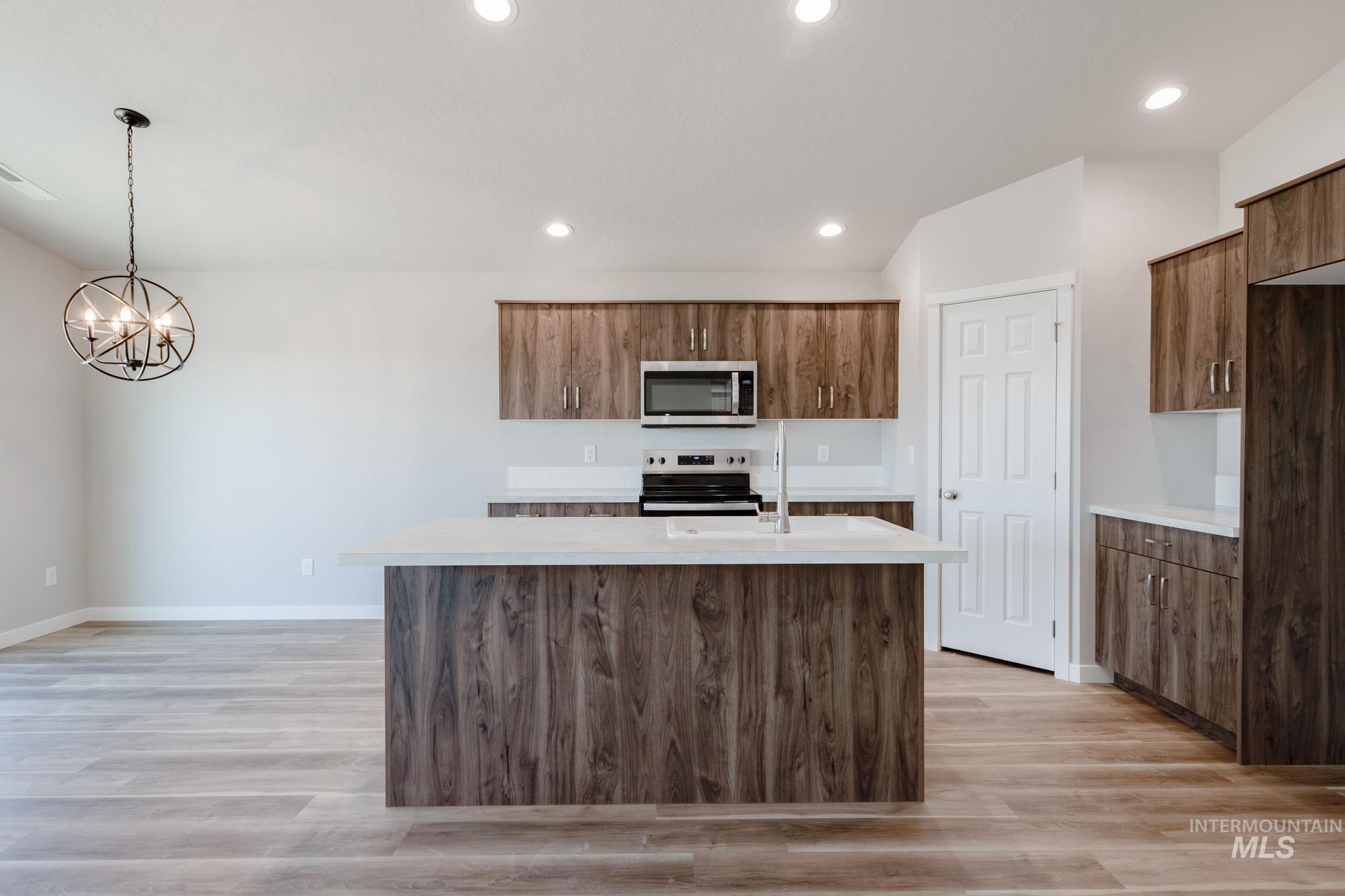 7256 South Menzingers Avenue Meridian, ID 83642 - Photo 3 of 23 Kitchen with a kitchen island with sink, decorative light fixtures, stainless steel appliances, light wood-style flooring, and recessed lighting