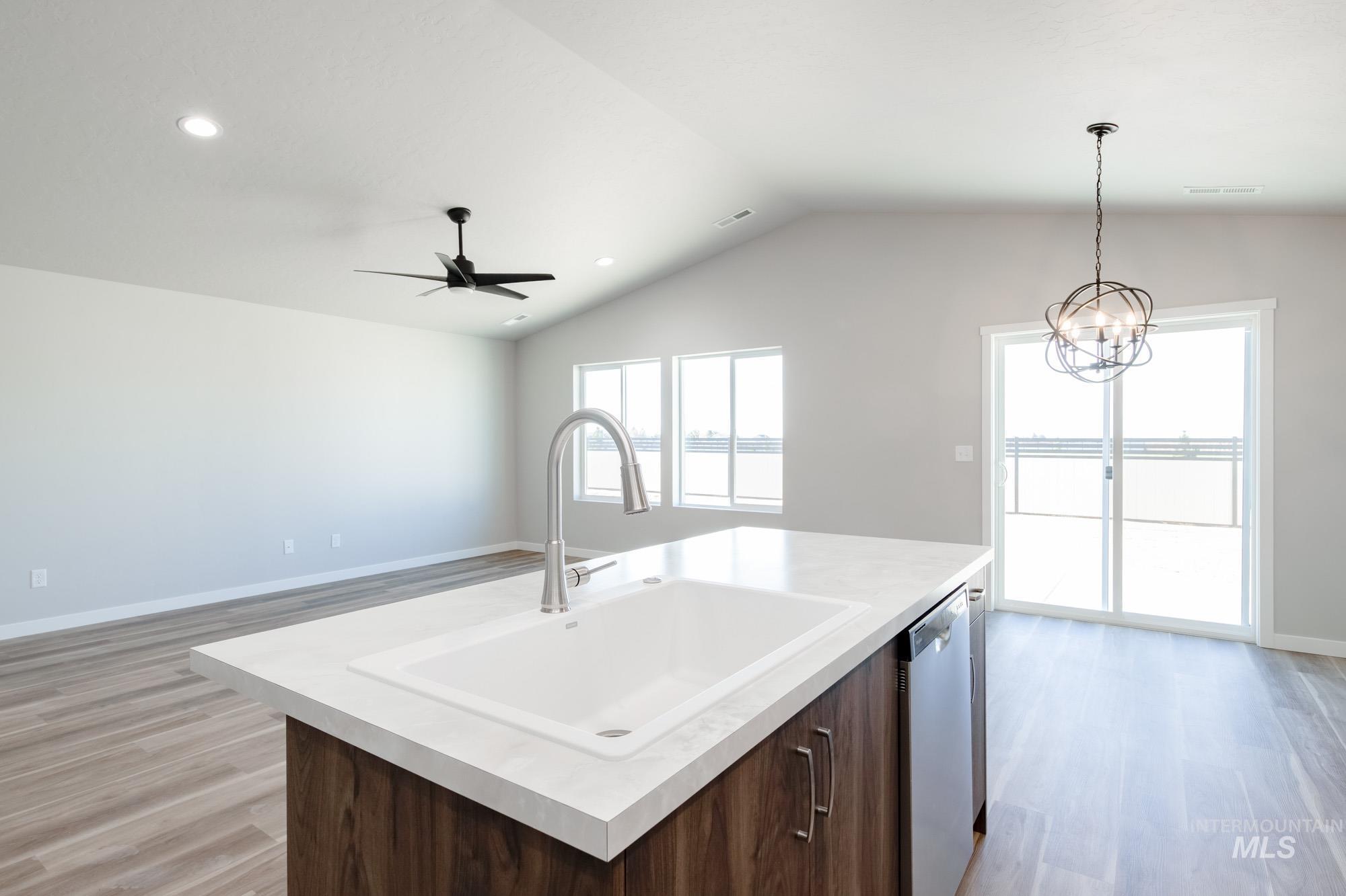 7256 South Menzingers Avenue Meridian, ID 83642 - Photo 22 of 23 Kitchen with dark brown cabinetry, light countertops, open floor plan, light wood finished floors, and vaulted ceiling