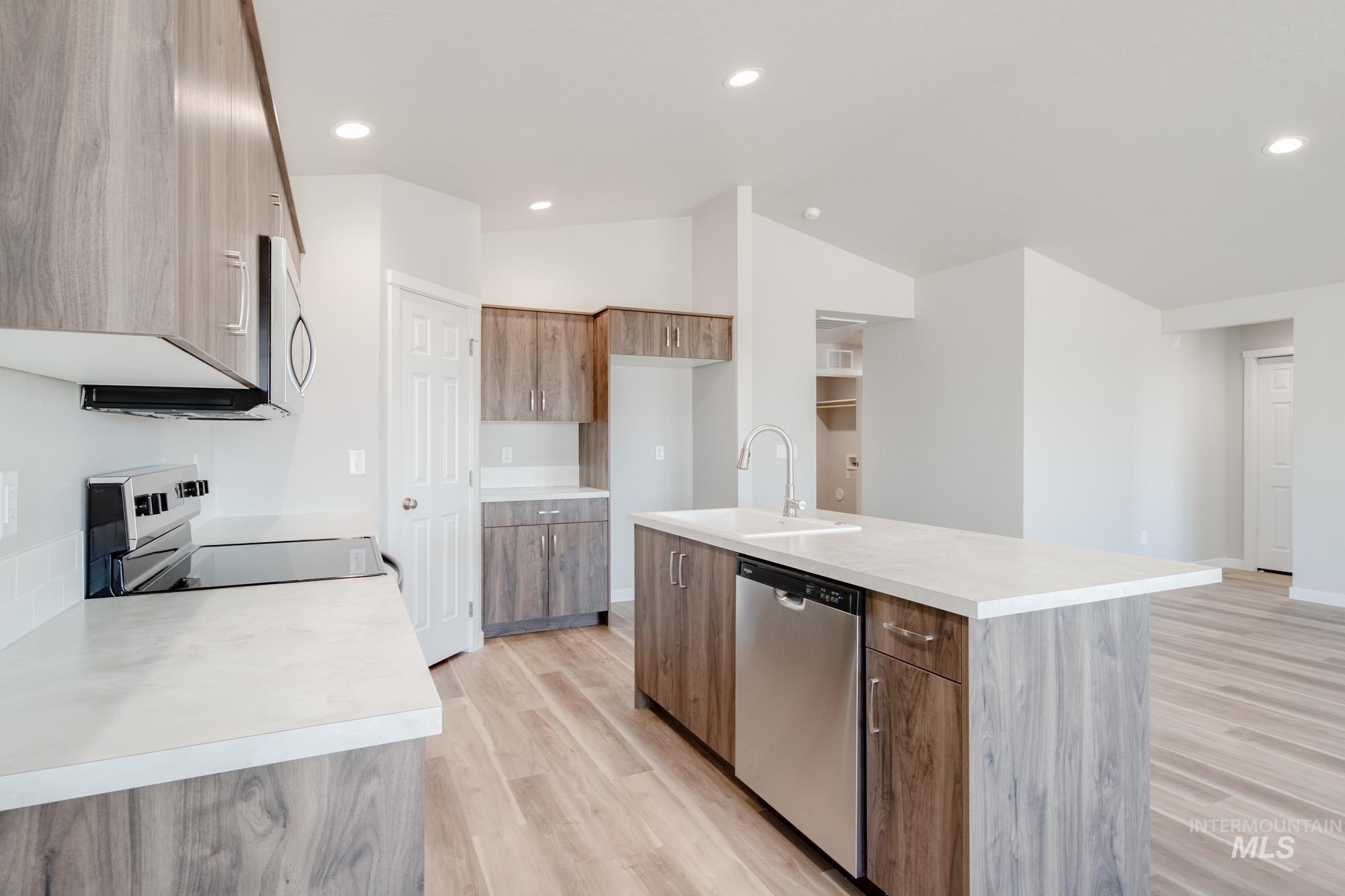 7256 South Menzingers Avenue Meridian, ID 83642 - Photo 6 of 23 Kitchen with light countertops, stainless steel appliances, light wood-type flooring, a kitchen island with sink, and recessed lighting