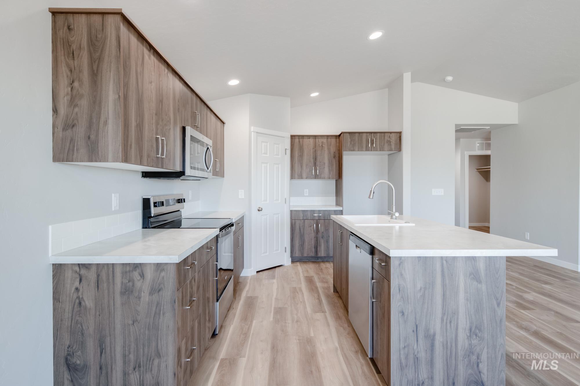 7256 South Menzingers Avenue Meridian, ID 83642 - Photo 7 of 23 Kitchen with appliances with stainless steel finishes, an island with sink, light wood-style floors, modern cabinets, and recessed lighting