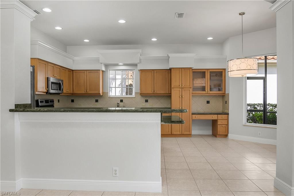 10160 Ginger Pointe Court Estero, FL 34135 - Photo 11 of 37 a large kitchen with stainless steel appliances a large counter top a stove a sink a refrigerator and a window