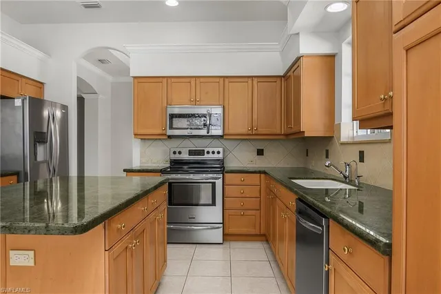 a kitchen with stainless steel appliances granite countertop a sink a stove and a refrigerator