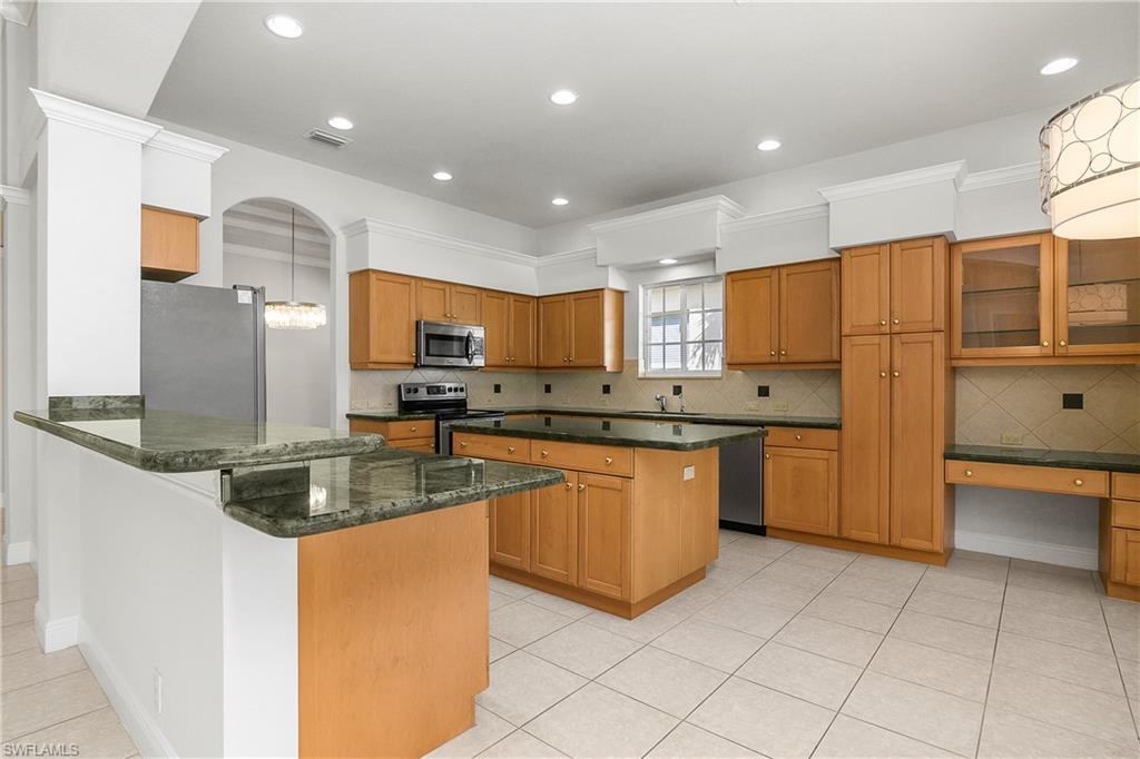 10160 Ginger Pointe Court Estero, FL 34135 - Photo 18 of 37 a kitchen with stainless steel appliances granite countertop a stove a sink and a refrigerator