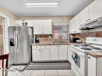 a kitchen with granite countertop a refrigerator stove top oven and sink