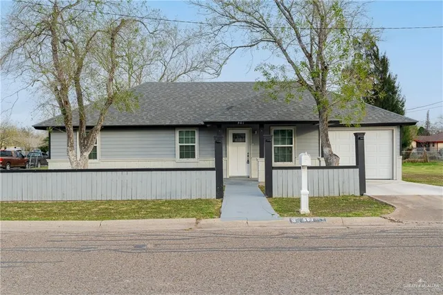 a front view of a house with a garden and a tree