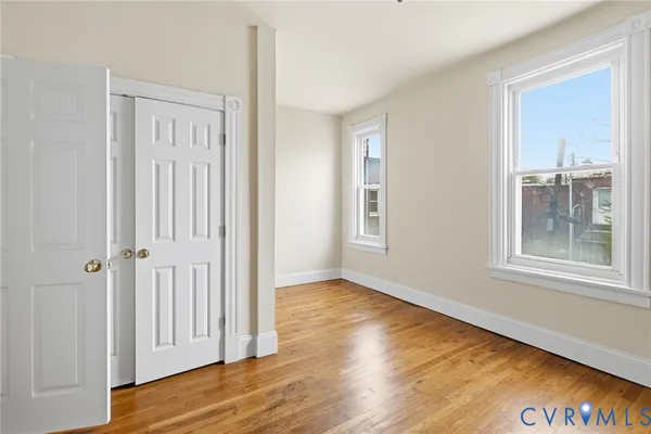 an empty room with wooden floor and windows