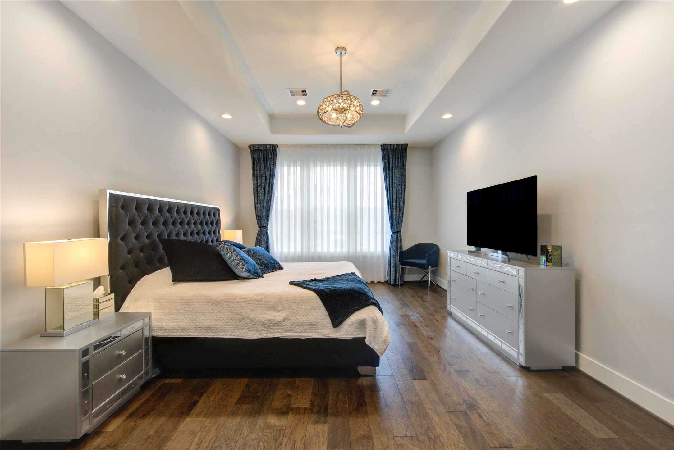 419 Malone Street Houston, TX 77007 - Photo 22 of 47 Located on the second floor, the primary bedroom showcases rich engineered hardwood flooring and a sophisticated modern chandelier, offering a luxurious and serene retreat