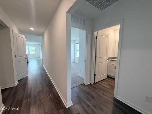 a view of a hallway with wooden floor and a kitchen