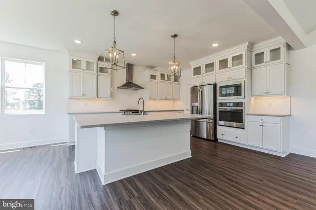 a kitchen with stainless steel appliances granite countertop wooden floors and white cabinets