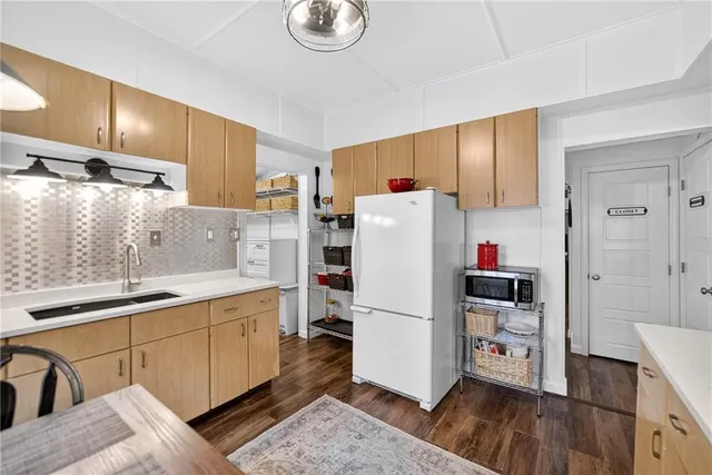 a kitchen with a refrigerator a sink and wooden floor