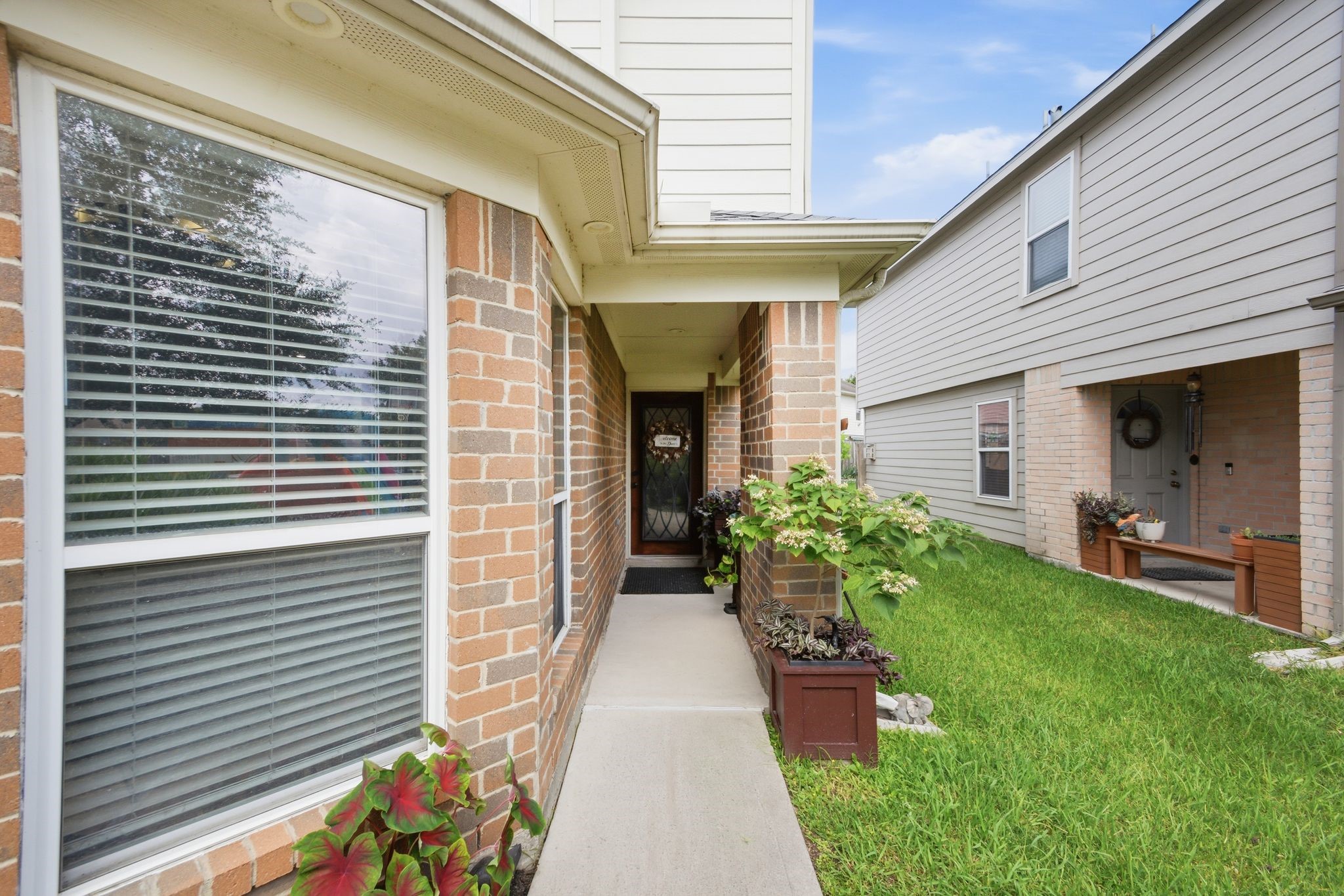 16954 Tableland Trail Conroe, TX 77385 - Photo 4 of 33 A welcoming front entrance surrounded by lush landscaping and timeless brick architecture, setting the tone for the comfort and style found throughout the home