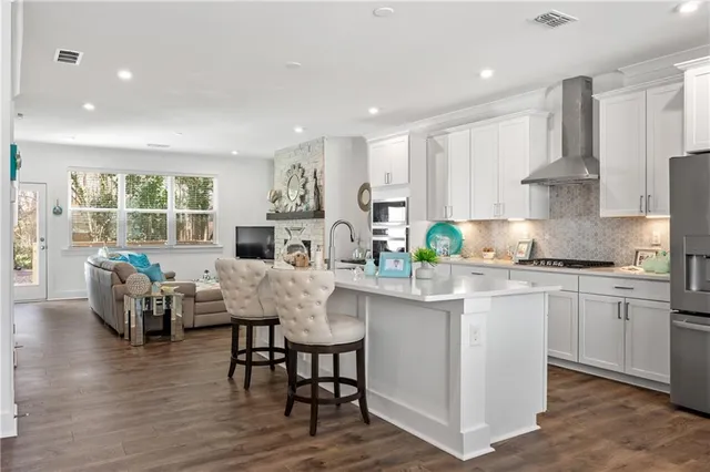 a kitchen with stainless steel appliances granite countertop a sink a stove and white cabinets
