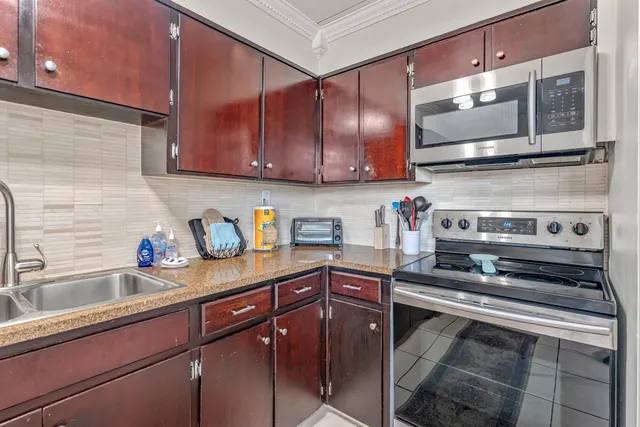 a kitchen with stainless steel appliances granite countertop a refrigerator a sink and a stove