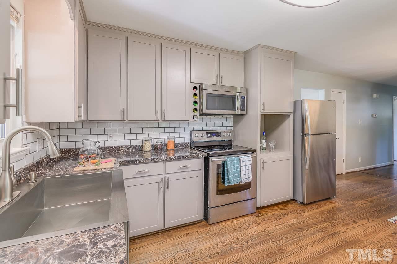 4105 Suitt Road Durham, NC 27703 - Photo 7 of 15 a kitchen with kitchen island a sink stainless steel appliances and cabinets