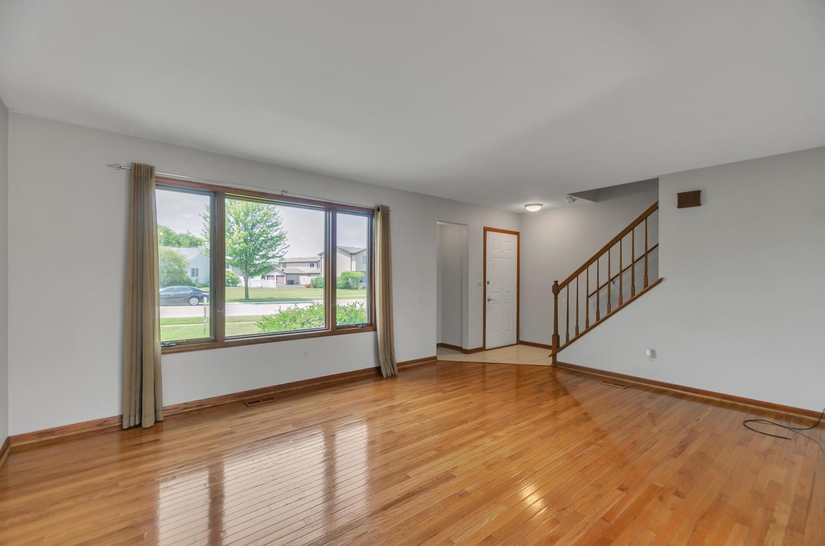 722 Sojourn Road New Lenox, IL 60451 - Photo 5 of 23 a view of an empty room with wooden floor and a window