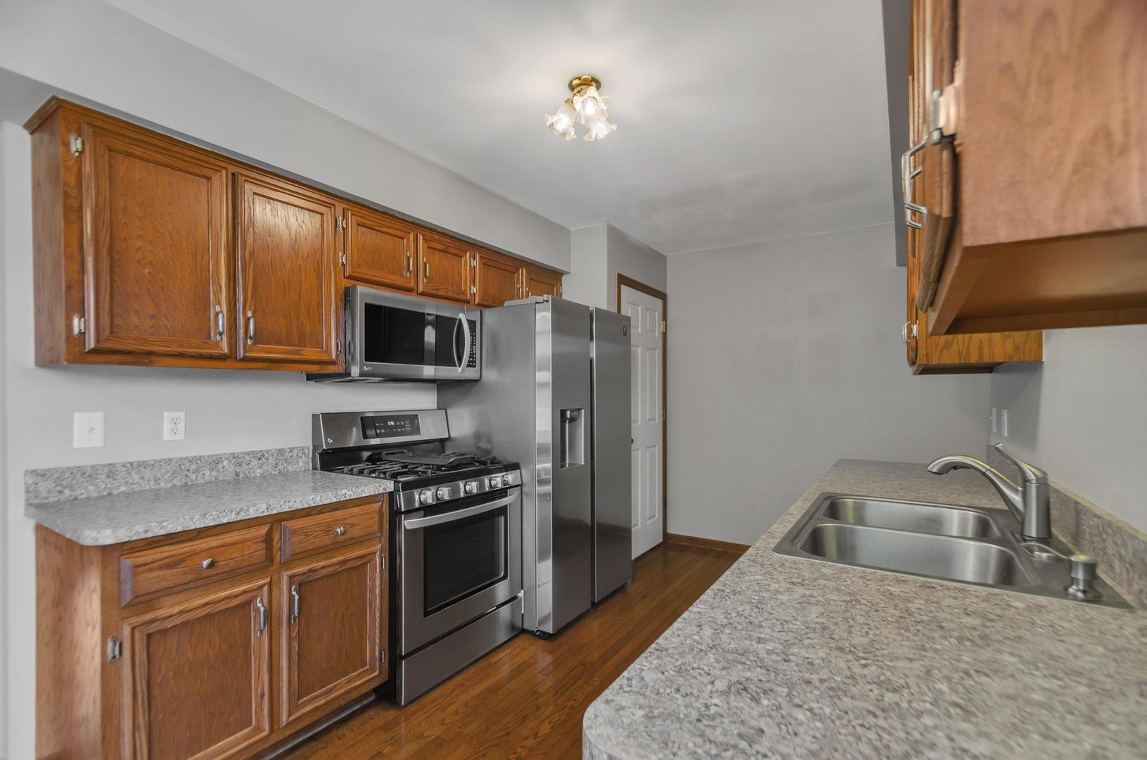 722 Sojourn Road New Lenox, IL 60451 - Photo 8 of 23 a kitchen with stainless steel appliances granite countertop a sink stove microwave and refrigerator