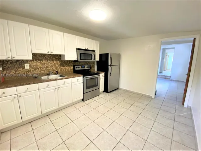 a kitchen with stainless steel appliances a sink a stove a microwave a counter top space and cabinets