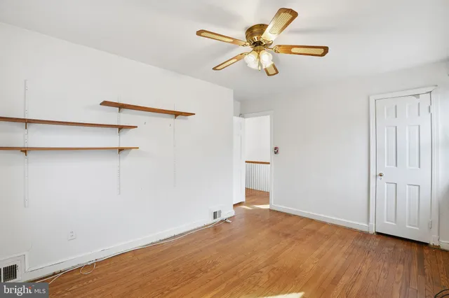 a view of a room with wooden floor and a ceiling fan