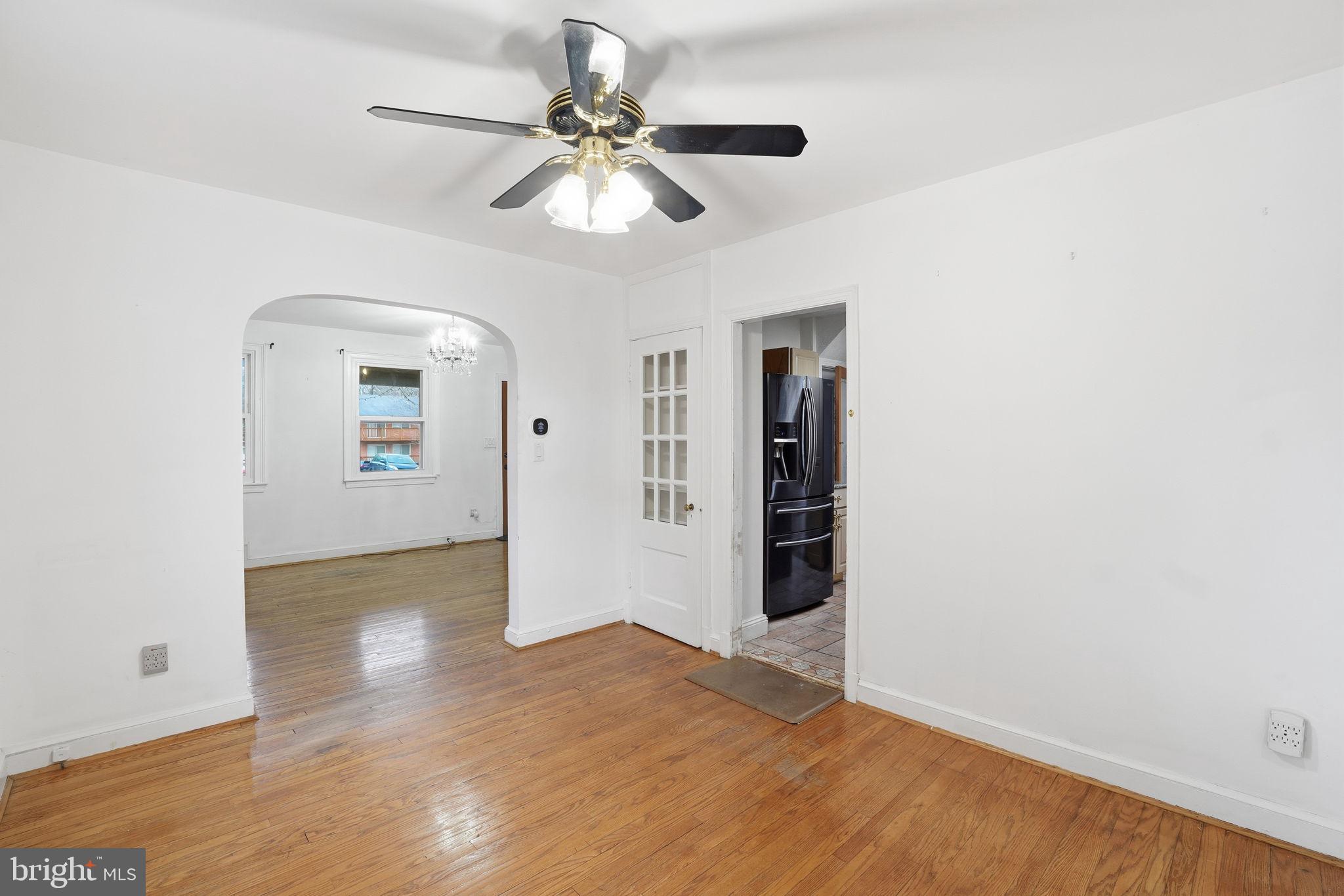 6758 Eastern Avenue Northwest Washington, DC 20012 - Photo 8 of 35 an empty room with wooden floor chandelier fan and windows