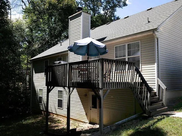 a view of a patio with a table and chairs with wooden floor and fence and a trees