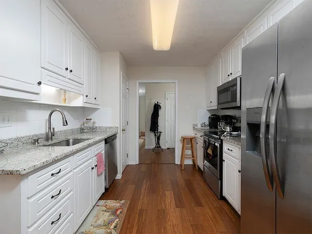 a kitchen with granite countertop stainless steel appliances a sink and refrigerator