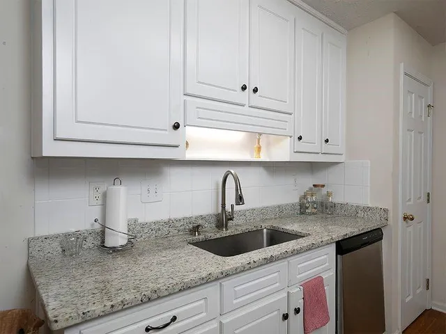 a kitchen with stainless steel appliances granite countertop white cabinets and a sink