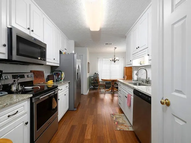 a kitchen with stainless steel appliances a stove top oven a sink dishwasher and a refrigerator