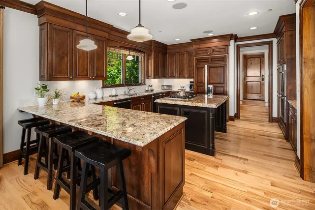 a kitchen with granite countertop a stove a sink dishwasher and a refrigerator with wooden floor