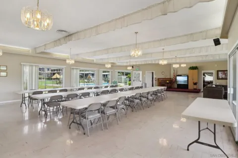 a room with lots of tables a chandelier and couches