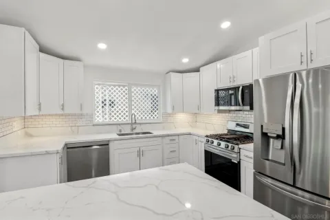 a kitchen with kitchen island a white counter top space cabinets and stainless steel appliances
