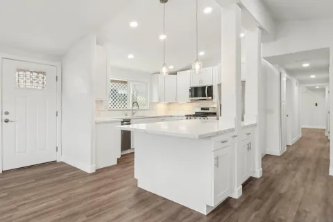 a kitchen with kitchen island a white counter top space cabinets and stainless steel appliances