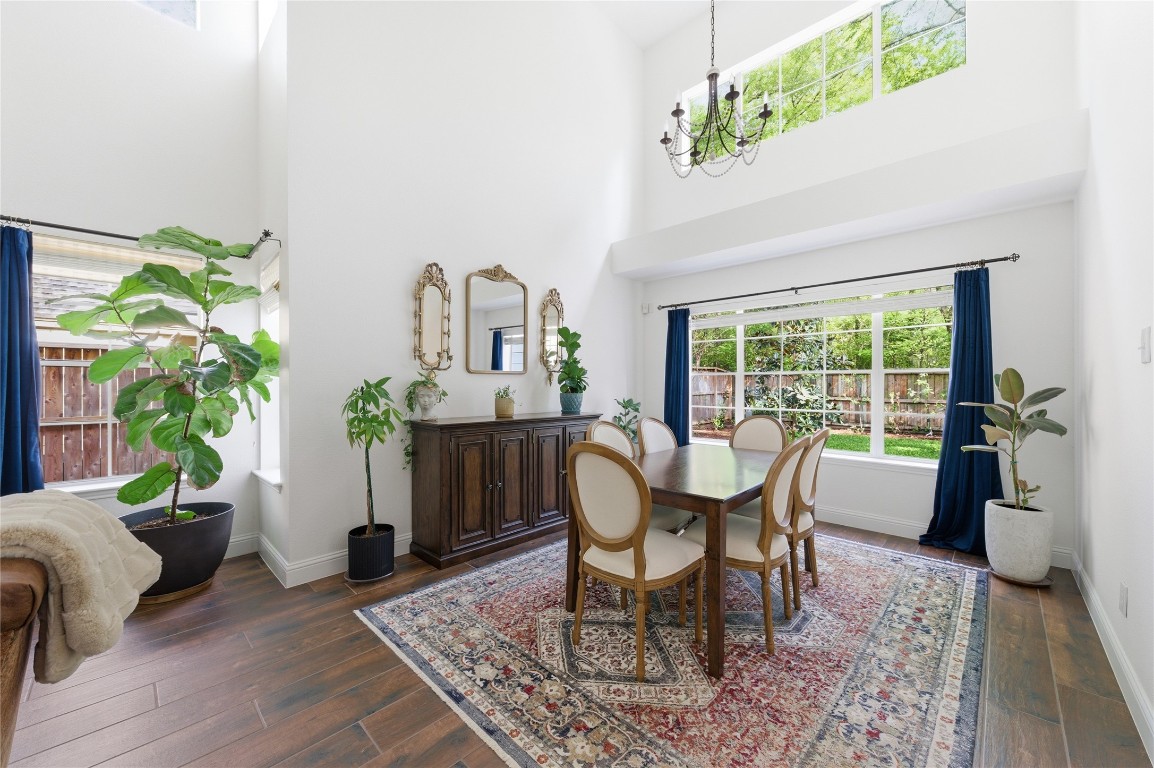 50 East Greywing Circle Spring, TX 77382 - Photo 12 of 37 Bright dining room with high ceilings and large windows. Features include dark wood flooring and a classic chandelier. Lush greenery adds a touch of nature.